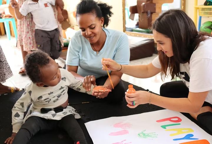 Volunteers playing with children at a craft table