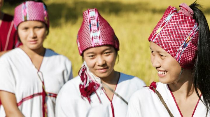 Young women in traditional headdresses smiling together