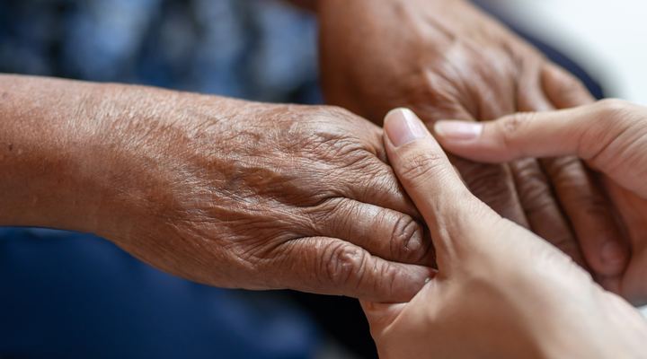 An older hand holding a younger hand